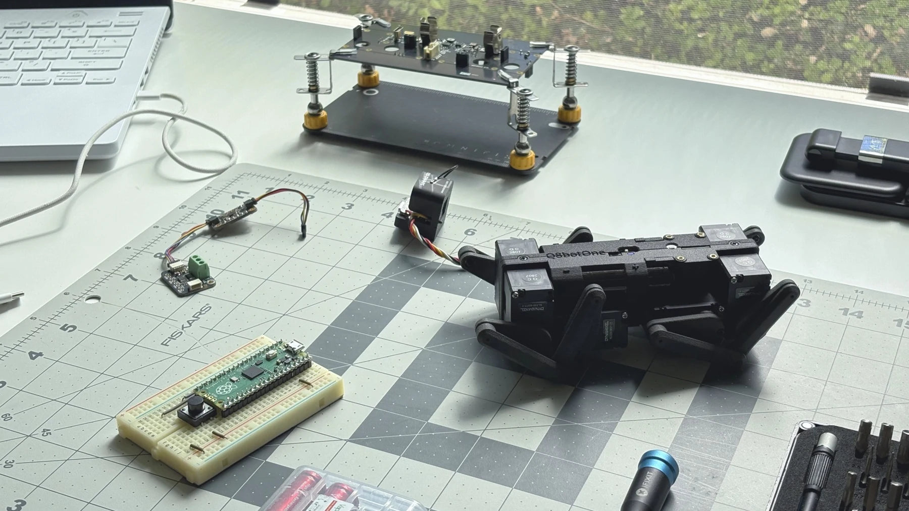 Q8botOne on a workbench alongside robot prototypes and electronics